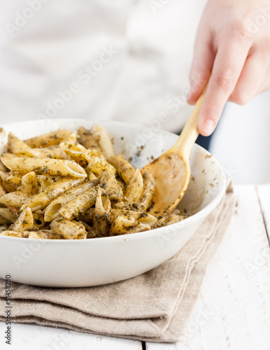 Photo: Cook mixing pesto with penne rigate pasta Cook mixing pesto with penne rigate pasta