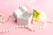 Beautiful box with wedding ring and flower on pink background