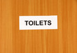Toilet sign on wooden background