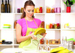 Beautiful young woman wipes clean utensils in kitchen