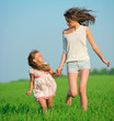 Young happy girls running at green wheat field