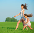 Photo: Young happy girls running at green wheat field Young happy girls running at green wheat field