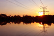 Electricity pylon with reflection in water at sunset