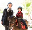 Mother riding her son on a pony