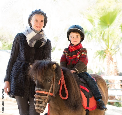 Photo: Mother riding her son on a pony Mother riding her son on a pony