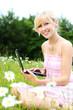 blonde frau mit laptop auf der wiese