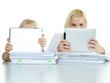 Two pupils leaning on a pile of paper while reading on touchpad