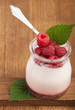 White yogurt in a glass jar with raspberry on wooden boards