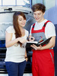 Car mechanics and customer look at the service record