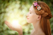 Beautiful fairy woman with glow in hands on natural green backgr