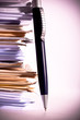 a pen near stack of paper