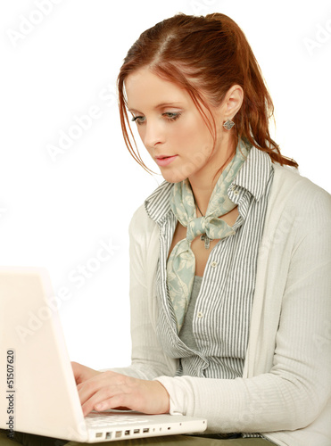 Photo: A young woman with a laptop sitting isolated on white background A young woman with a laptop sitting isolated on white background