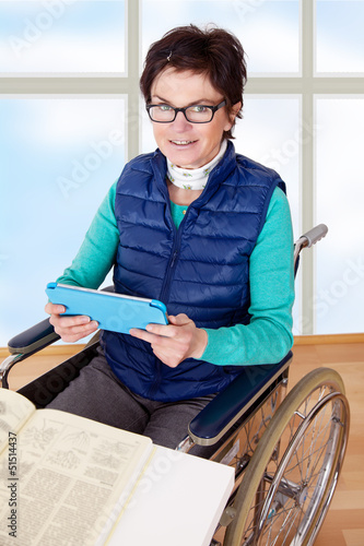 Photo: Woman with Tablet PC's in a wheelchair at the table Woman with Tablet PC's in a wheelchair at the table
