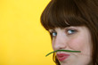 Photo: Woman holding a green bean between her lips and her nose Woman holding a green bean between her lips and her nose