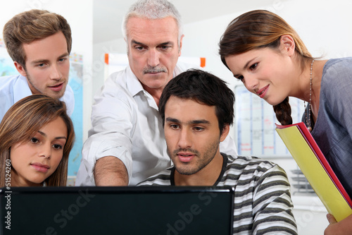 Photo: Older students and teacher gathered round a computer Older students and teacher gathered round a computer