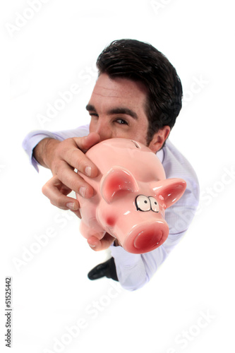 Photo: Man standing on white background showing piggy bank Man standing on white background showing piggy bank