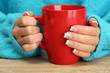 hands holding mug of hot drink, close-up