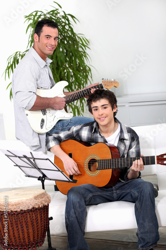 Photo: Father teaching son how to play the guitar Father teaching son how to play the guitar