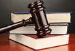 Wooden gavel and books on grey background
