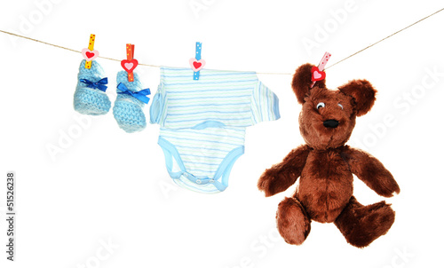 Photo: Baby clothes hanging on clothesline, isolated on white Baby clothes hanging on clothesline, isolated on white
