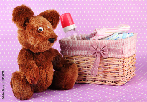 Photo: Beautiful basket of baby clothes on a pink background Beautiful basket of baby clothes on a pink background