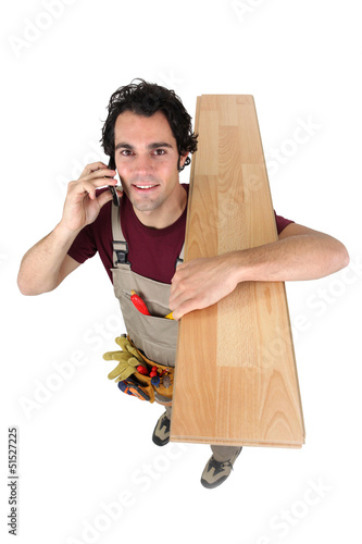 Photo: Worker on the phone while carrying wooden flooring Worker on the phone while carrying wooden flooring