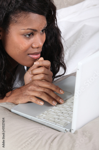 Photo: Black lady using laptop in bed Black lady using laptop in bed