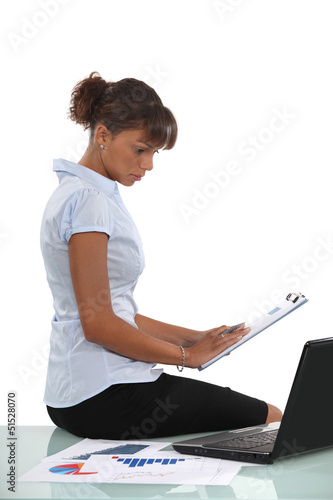 Photo: Woman sat with laptop and clip-board Woman sat with laptop and clip-board