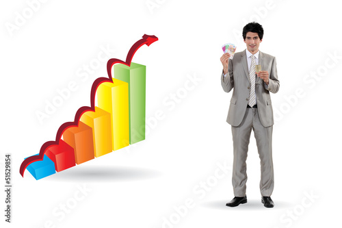 Photo: Businessman standing by bar chart holding cash Businessman standing by bar chart holding cash