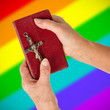 Old hands holding a very old bible, rainbow flag pattern