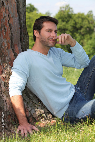 Photo: Man sitting against a tree. Man sitting against a tree.