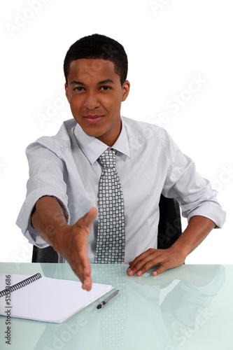 Photo: young black executive stretching out his hand to shake hands young black executive stretching out his hand to shake hands