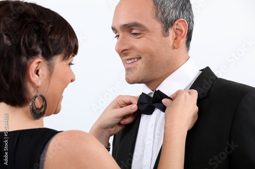 Photo: Wife helping husband with bow tie Wife helping husband with bow tie