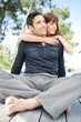 Man sitting cross-legged and being hugged by his wife