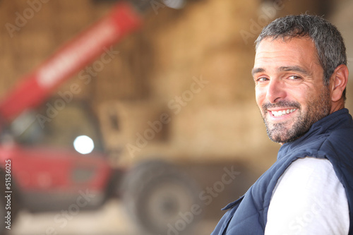 Photo: Farmer stood in front of bails of hay Farmer stood in front of bails of hay