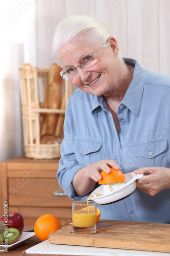 Photo: Elderly woman pouring freshly squeezed orange juice Elderly woman pouring freshly squeezed orange juice