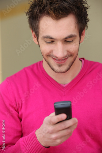 Photo: Young man smiling at his phone Young man smiling at his phone