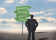 Businessman looking at signposts with marketing terms