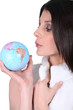 Foto: Woman blowing on a mini globe Woman blowing on a mini globe