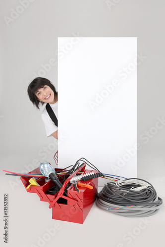 Photo: Woman electrician behind white panel Woman electrician behind white panel
