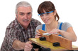 Woodworker and female apprentice sanding wood