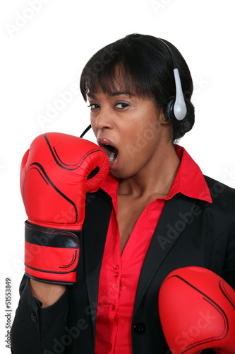 Photo: A black businesswoman yawning with boxing gloves on. A black businesswoman yawning with boxing gloves on.