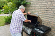 Senior man cleaning barbecue