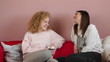 Two female friends sitting on the sofa and chatting