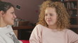 Two female friends sitting on the sofa and chatting
