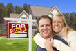Photo: Couple in Front of Sold Real Estate Sign and House Couple in Front of Sold Real Estate Sign and House