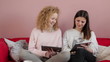Two female friends sitting on the sofa with tablet computer