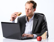 Hardworking man eating at his desk through lunch break hour