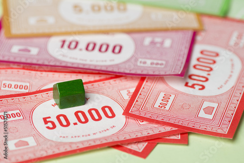 Photo: Green house and bank notes on monopoly game board Green house and bank notes on monopoly game board