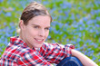 Young attractive woman sitting on a meadow with Scilla bifolia